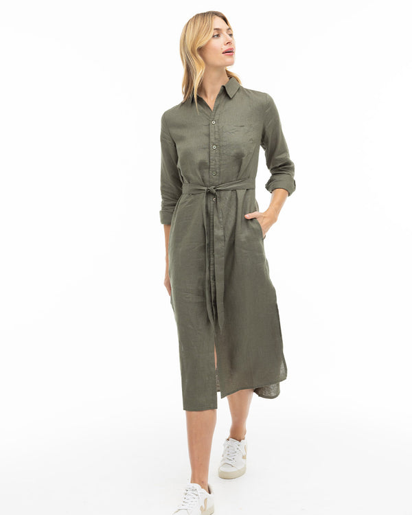 LIFESTYLE / EDITORIAL: Woman wearing dark olive shirt dress with belt and white sneakers walking against white background