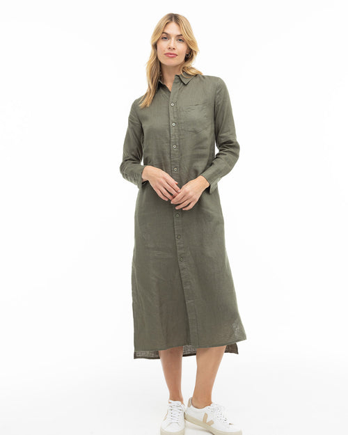 Woman wearing a dark olive long-sleeve button-down midi dress with white sneakers, standing against white background
