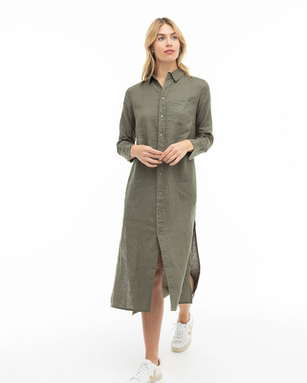 Woman wearing dark olive long button-up shirt dress with white sneakers on white background