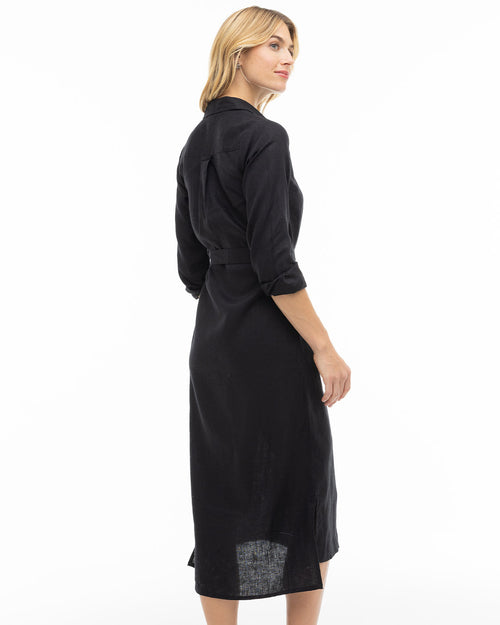 LIFESTYLE / EDITORIAL: Woman wearing a long black shirt dress, standing sideways against a white background