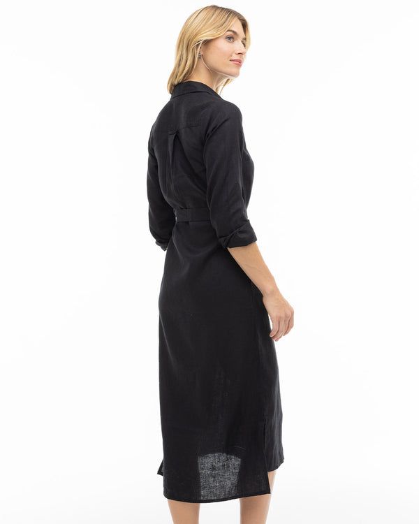 LIFESTYLE / EDITORIAL: Woman wearing a long black shirt dress, standing sideways against a white background
