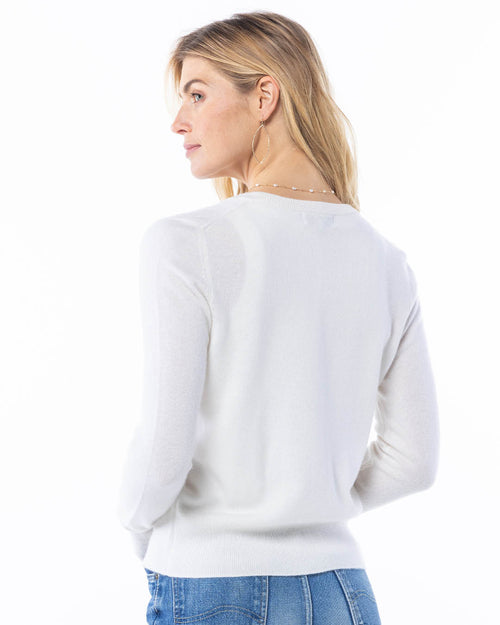 LIFESTYLE / EDITORIAL: Woman in white cashmere sweater and blue jeans, facing sideways against white background