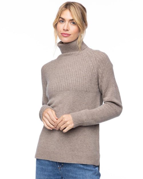 Front three-quarter view image of a woman wearing a vintage khaki half-rib turtleneck cashmere sweater with blue jeans