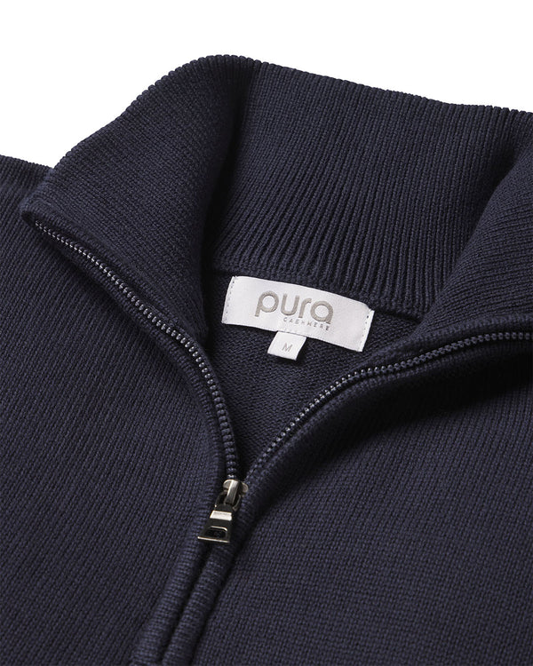 Close-up of navy blue cashmere sweater collar with zipper and "pura" brand label in size medium