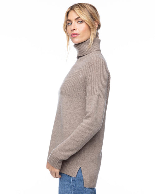 Woman in vintage khaki half-rib turtleneck cashmere sweater, side view, wearing blue jeans against white background
