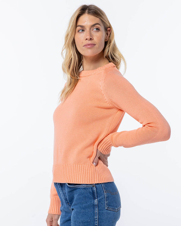LIFESTYLE / EDITORIAL: Woman wearing coral cashmere sweater and blue jeans, posing against white background