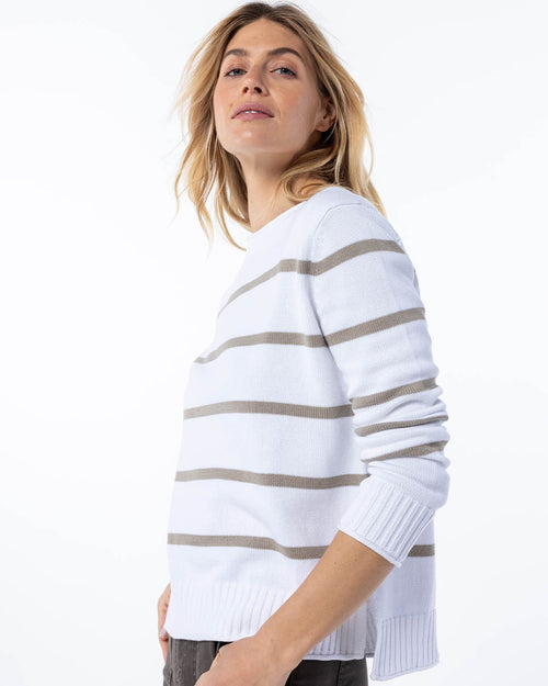 Side view image of a woman wearing white cashmere sweater with mushroom horizontal stripes, posing with hands in pockets