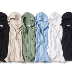 Six ribbed cashmere hooded zip sweaters in black, beige, green, blue, white, and navy laid flat side by side