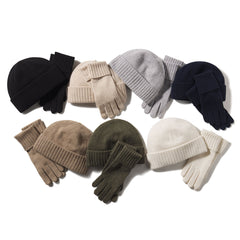 Six pairs of cashmere gloves and matching beanies in black, beige, gray, navy, brown, olive, and white arranged on white