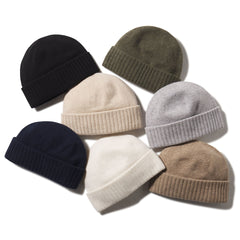 Six folded cashmere beanies in black, olive, beige, gray, navy, white, and tan on white background