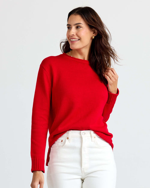 LIFESTYLE / EDITORIAL: Woman wearing red cashmere sweater and white pants, smiling and looking to the side