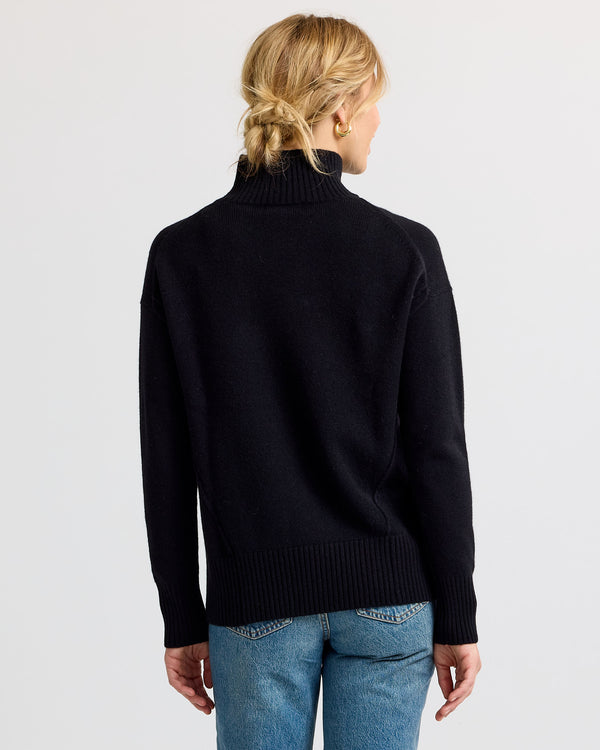 Black cashmere funnel neck sweater with blue jeans, back view