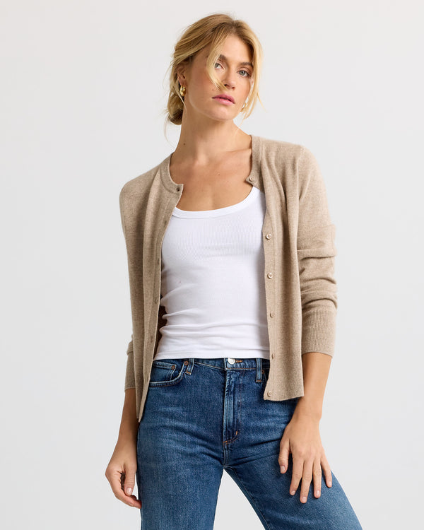 LIFESTYLE / EDITORIAL: Woman wearing driftwood beige cashmere cardigan over white tank and blue jeans against white