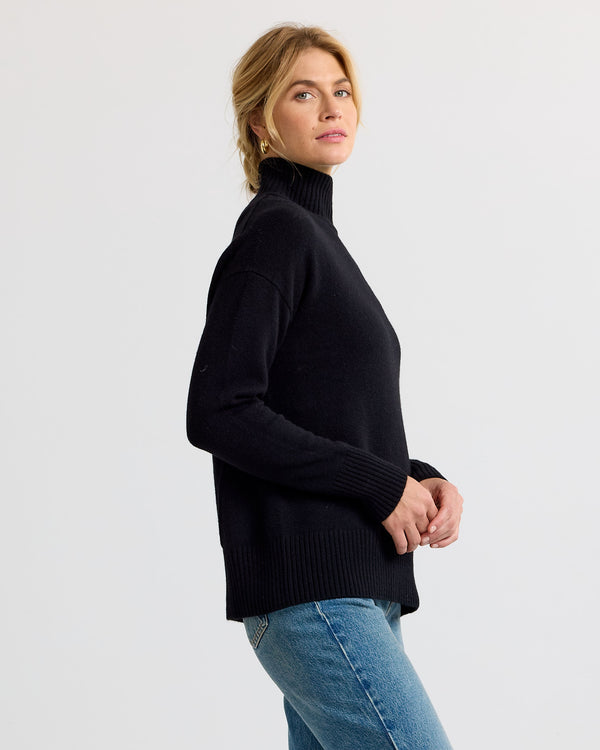 Black cashmere funnel neck sweater with blue jeans, side view