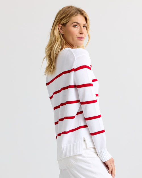 Side view image of a woman wearing a white and red striped cashmere sweater, looking back over her shoulder.