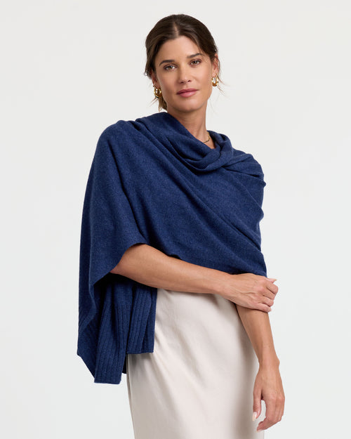 LIFESTYLE / EDITORIAL: Woman wearing indigo cashmere wrap over white dress, standing against plain background