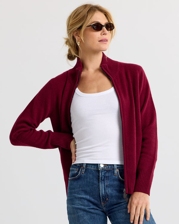 Woman wearing barolo red zip-up cashmere cardigan over white tank top and blue jeans, sunglasses on head