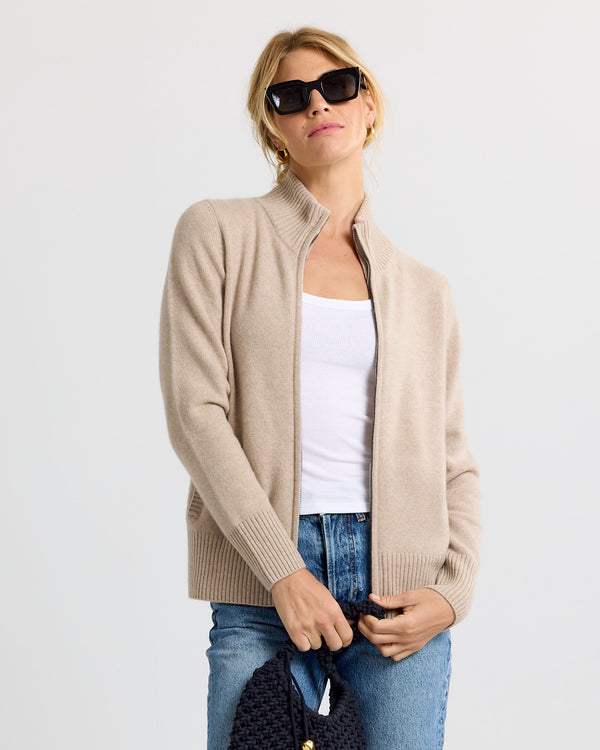 LIFESTYLE / EDITORIAL: Woman wearing cappuccino cashmere zip-up sweater, white tank top, blue jeans, and black sunglasses