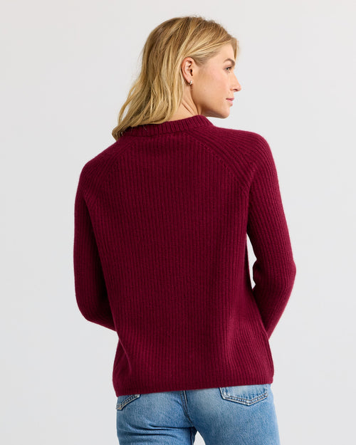 LIFESTYLE / EDITORIAL: Woman wearing a barolo red ribbed cashmere sweater, viewed from the back, paired with blue jeans