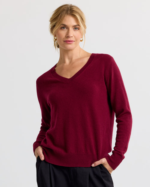 LIFESTYLE / EDITORIAL: Woman wearing a barolo-colored V-neck cashmere sweater with black pants, hands in pockets