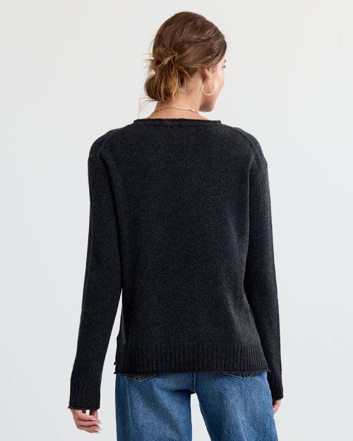 Woman wearing charcoal cashmere sweater and blue jeans, shown from the back against a plain background