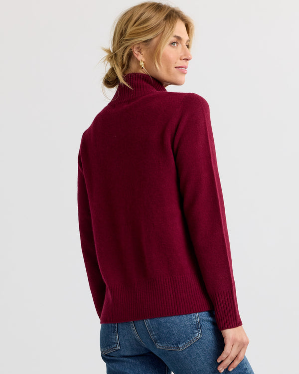 LIFESTYLE / EDITORIAL: Woman wearing a barolo red turtleneck cashmere sweater, shown from the back, paired with blue jeans