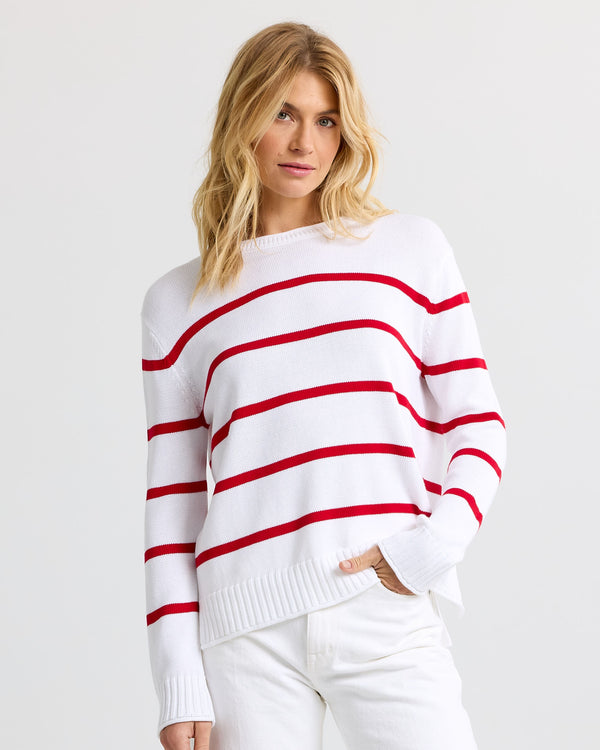 Three-quarter view image of a woman wearing a red and white striped cashmere sweater and white pants