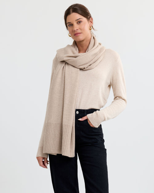 LIFESTYLE / EDITORIAL: Woman wearing beige cashmere sweater and scarf with black pants against white background