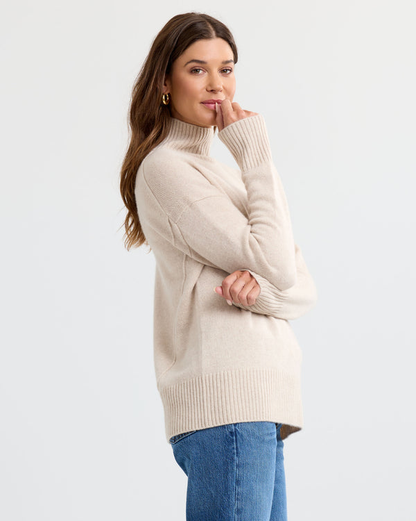 Oatmeal cashmere funnel neck sweater with blue jeans, side view