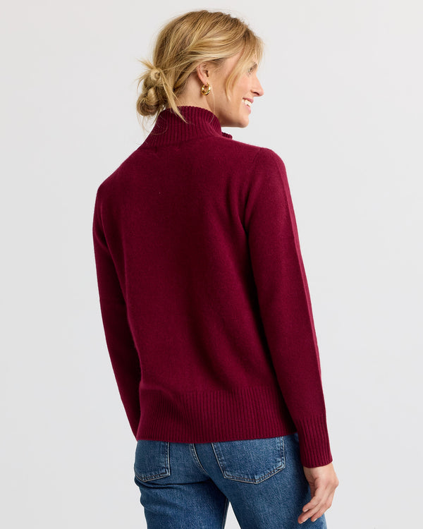 LIFESTYLE / EDITORIAL: Woman wearing a barolo red turtleneck cashmere sweater and blue jeans, viewed from the back