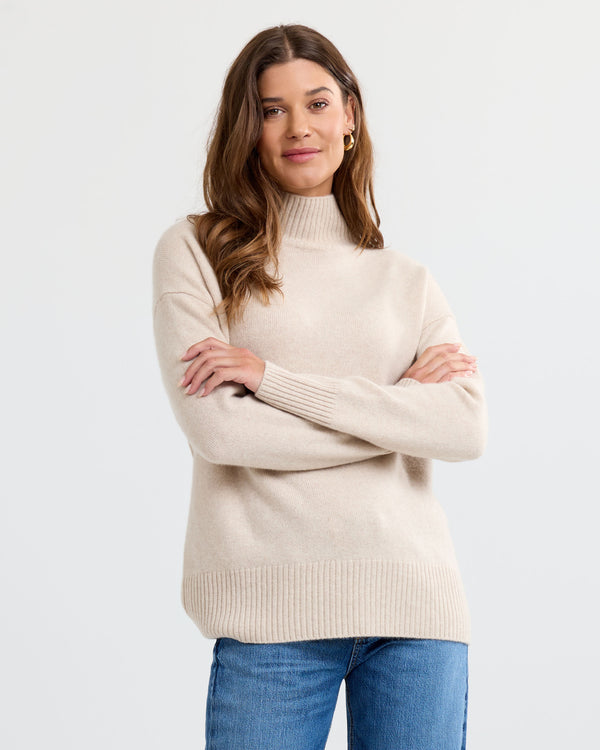 Oatmeal cashmere funnel neck sweater with blue jeans, front view with arms crossed