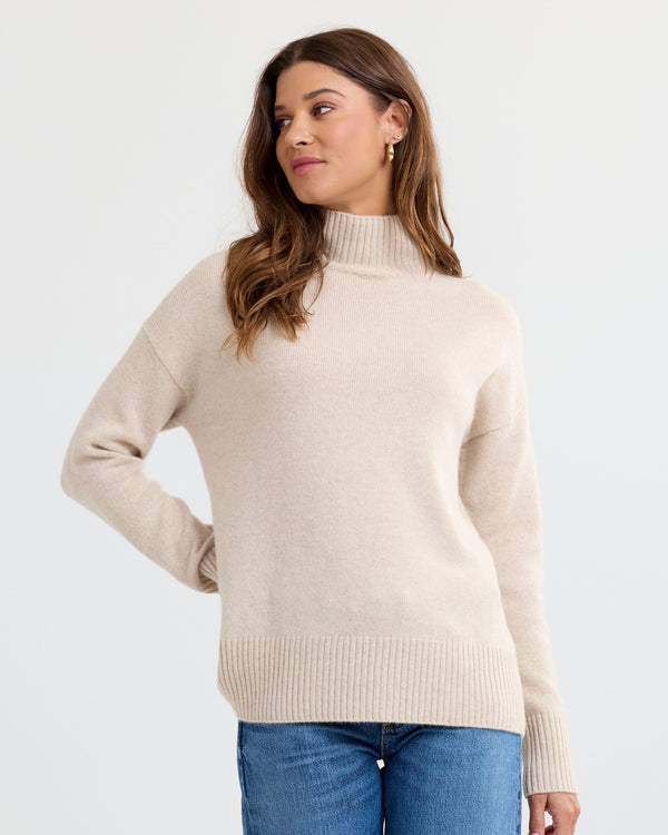 Oatmeal cashmere funnel neck sweater with blue jeans, three-quarter view