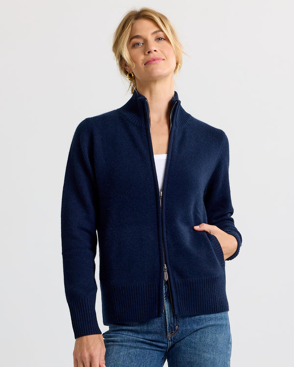LIFESTYLE / EDITORIAL: Woman wearing navy zip-up cashmere sweater with hand in pocket, paired with jeans and white top