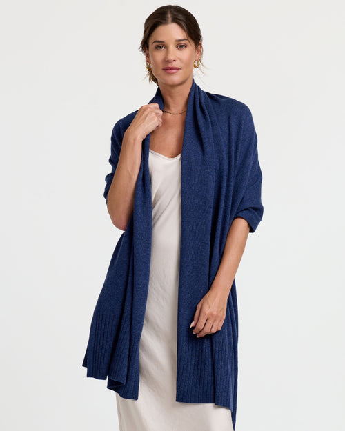 Front-facing image of a woman wearing an indigo blue cashmere shawl over a white dress against a plain background