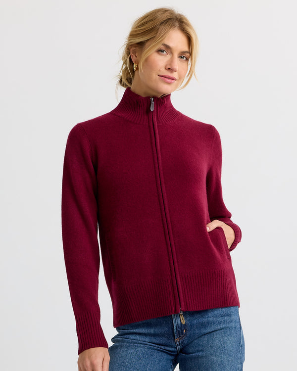 LIFESTYLE / EDITORIAL: Woman wearing a barolo red zip-up cashmere sweater with high collar and blue jeans against white