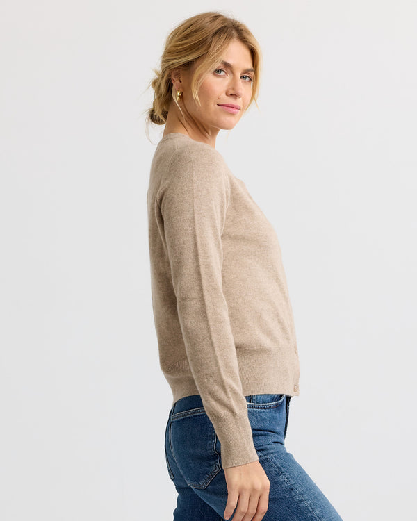 LIFESTYLE / EDITORIAL: Woman in beige cashmere sweater and blue jeans, side view against plain background