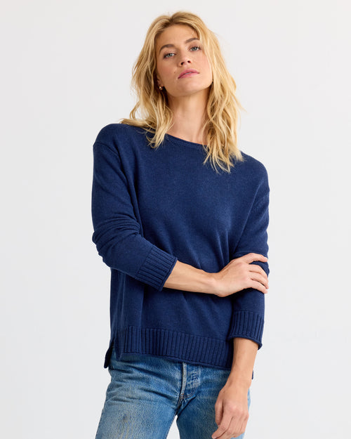 LIFESTYLE / EDITORIAL: Woman wearing navy blue cashmere sweater and jeans against white background