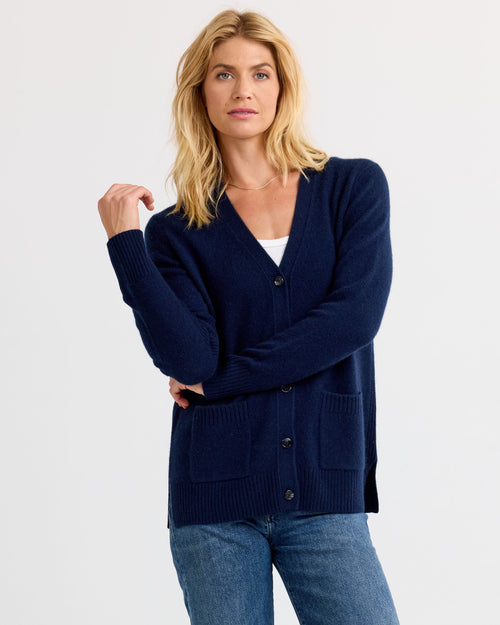 LIFESTYLE / EDITORIAL: Woman wearing navy cashmere cardigan and jeans against plain background