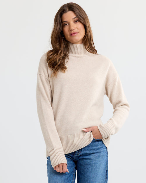 Oatmeal cashmere funnel neck sweater with blue jeans, standing front view