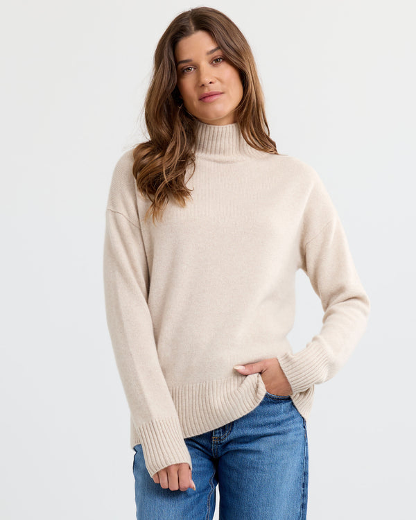 Oatmeal cashmere funnel neck sweater with blue jeans, standing front view
