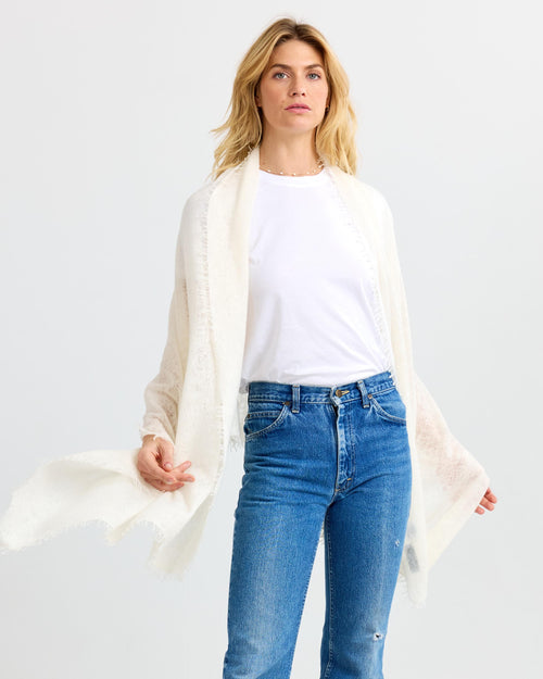 LIFESTYLE / EDITORIAL: Woman wearing white cashmere shawl, white t-shirt, and blue jeans against white background