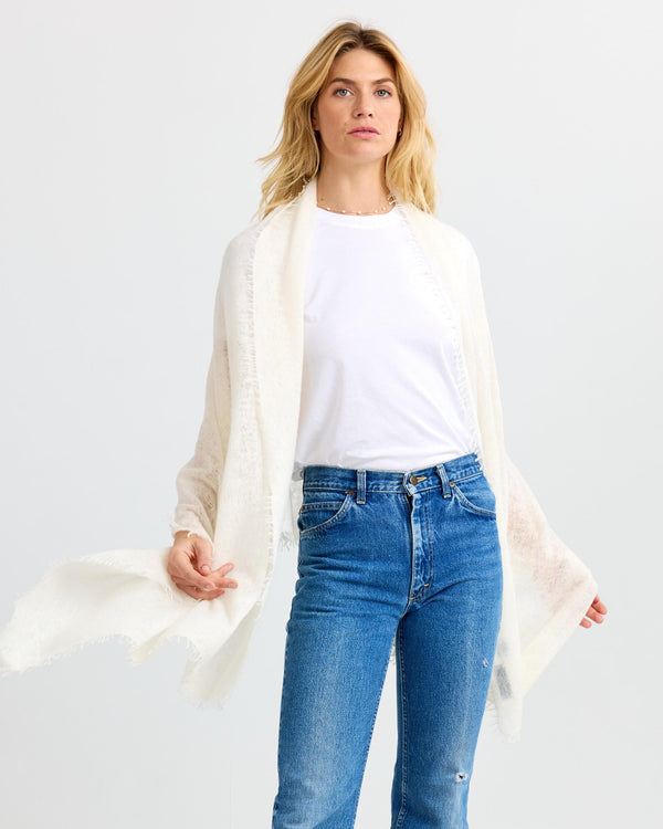 LIFESTYLE / EDITORIAL: Woman wearing white cashmere shawl, white t-shirt, and blue jeans against white background
