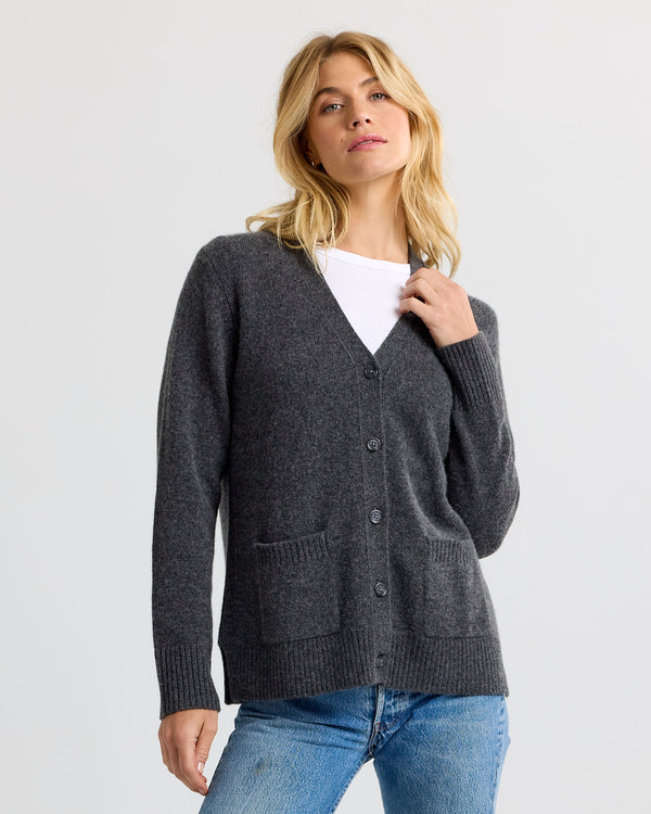 LIFESTYLE / EDITORIAL: Woman wearing charcoal gray cashmere cardigan over white shirt and blue jeans against plain background