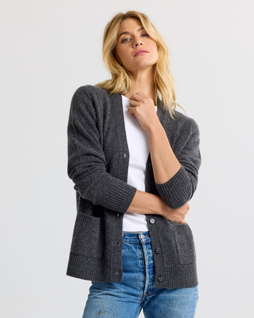 LIFESTYLE / EDITORIAL: Woman wearing charcoal gray cashmere cardigan over white top and blue jeans against plain background