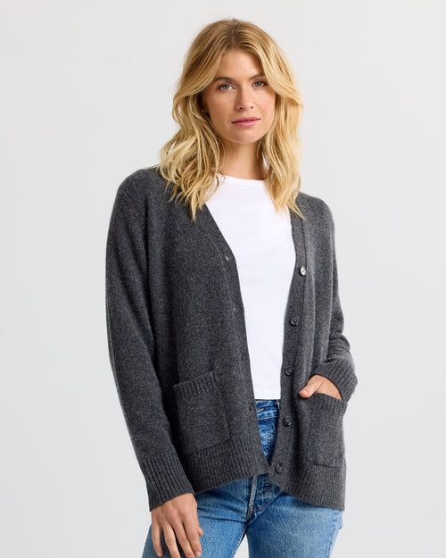 LIFESTYLE / EDITORIAL: Woman wearing charcoal gray buttoned cashmere cardigan over white shirt and blue jeans, standing