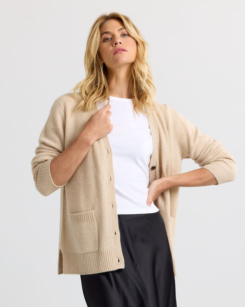 LIFESTYLE / EDITORIAL: Woman wearing sandstone beige cashmere cardigan over white top and black skirt against white