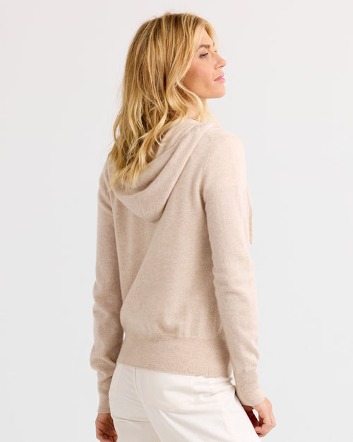 LIFESTYLE / EDITORIAL: Woman wearing oatmeal-colored cashmere hoodie, viewed from back against white background