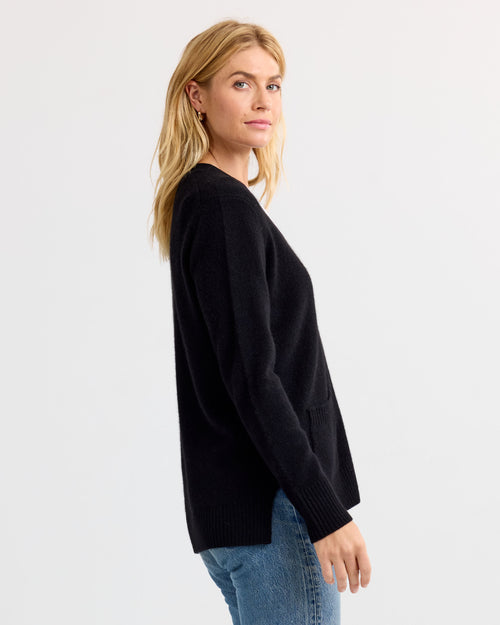 LIFESTYLE / EDITORIAL: Woman in black cashmere sweater and blue jeans, standing sideways against white background