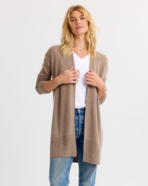 LIFESTYLE / EDITORIAL: Woman wearing long driftwood-colored cashmere cardigan over white V-neck shirt and blue jeans