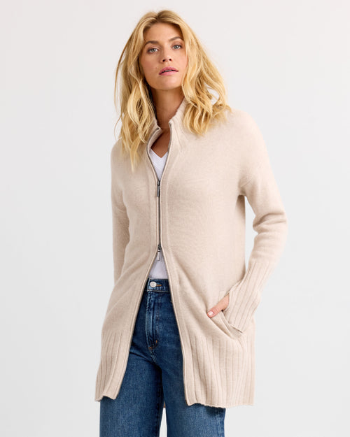 LIFESTYLE / EDITORIAL: Woman wearing oatmeal long zip-up cashmere cardigan with pockets and jeans against white background